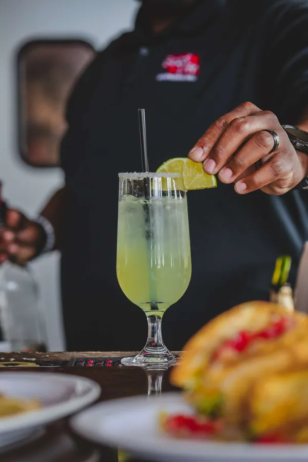 Lime garnish being added to a green cocktail